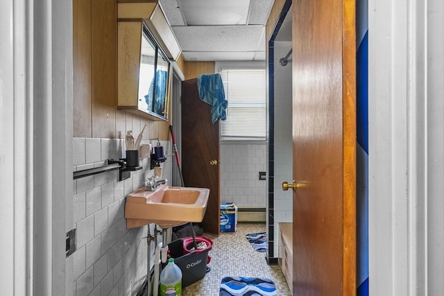 bathroom with sink, a drop ceiling, a baseboard heating unit, and tile patterned flooring