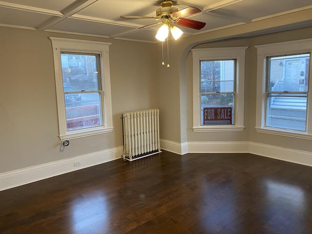 unfurnished room with dark hardwood / wood-style floors, plenty of natural light, radiator, and coffered ceiling