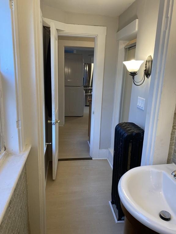 bathroom with hardwood / wood-style flooring, radiator, and sink