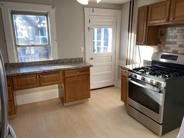 kitchen with light wood-type flooring, backsplash, and stainless steel range with gas cooktop