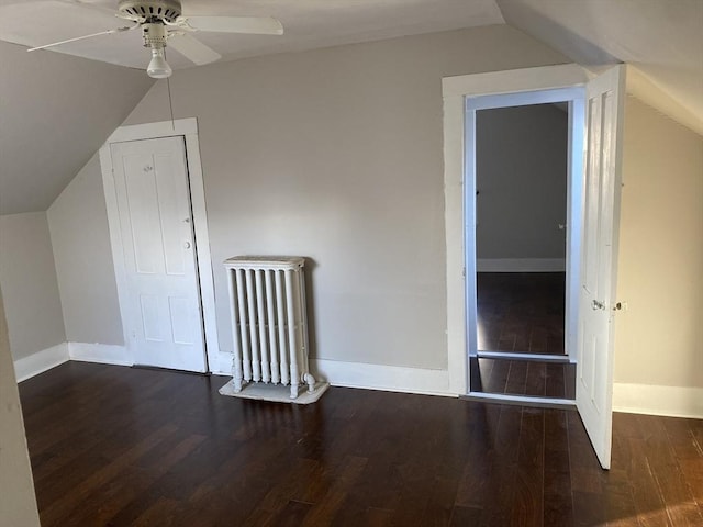 additional living space with ceiling fan, radiator heating unit, dark wood-type flooring, and vaulted ceiling