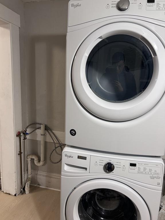 clothes washing area with stacked washer / dryer and light hardwood / wood-style flooring