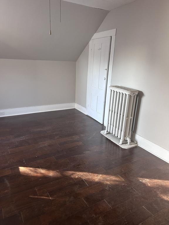 bonus room with radiator heating unit, vaulted ceiling, and dark wood-type flooring