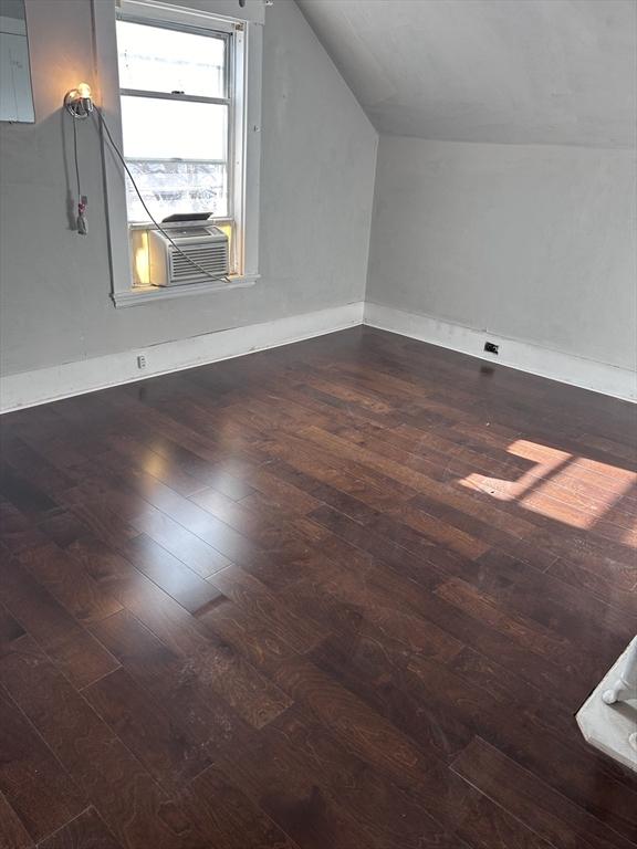 additional living space featuring vaulted ceiling, cooling unit, and dark wood-type flooring