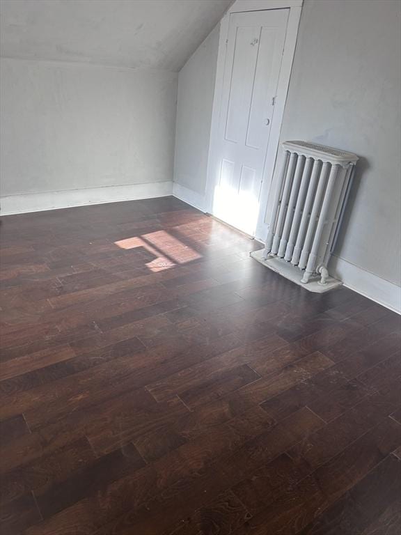 bonus room featuring radiator heating unit, vaulted ceiling, and dark wood-type flooring