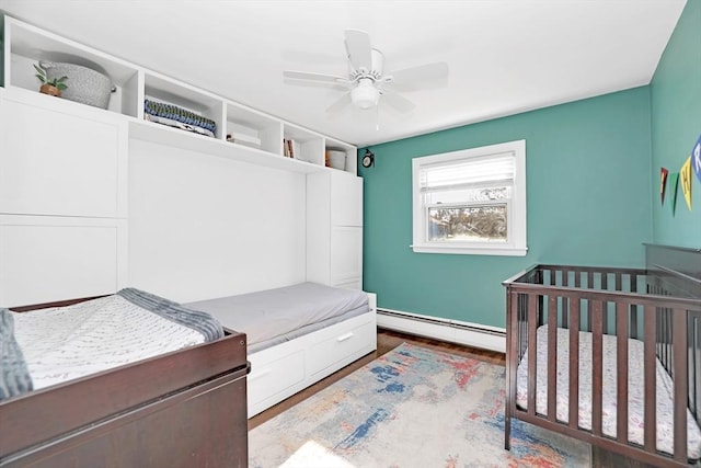 110 Walnut St, Canton, MA 02021 - bedroom featuring a baseboard heating unit, baseboards, wood finished floors, ceiling fan, and a nursery area