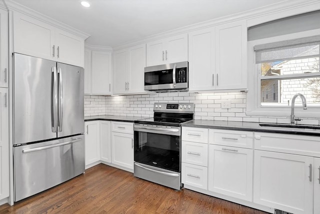 110 Walnut St, Canton, MA 02021 - kitchen featuring appliances with stainless steel finishes, a sink, dark countertops, white cabinetry, and decorative backsplash