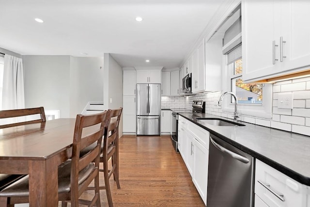 110 Walnut St, Canton, MA 02021 - kitchen featuring stainless steel appliances, a sink, wood finished floors, backsplash, and white cabinetry