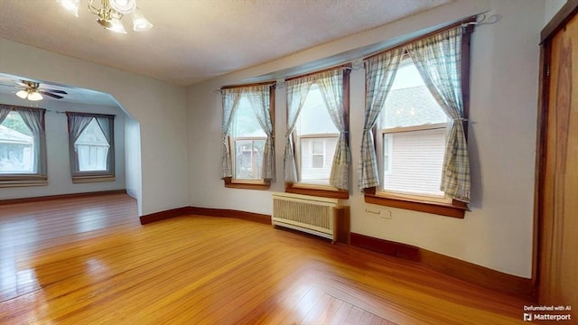 25 Garrison St, Fairhaven, MA 02719 - empty room featuring radiator, light wood-type flooring, arched walkways, and ceiling fan