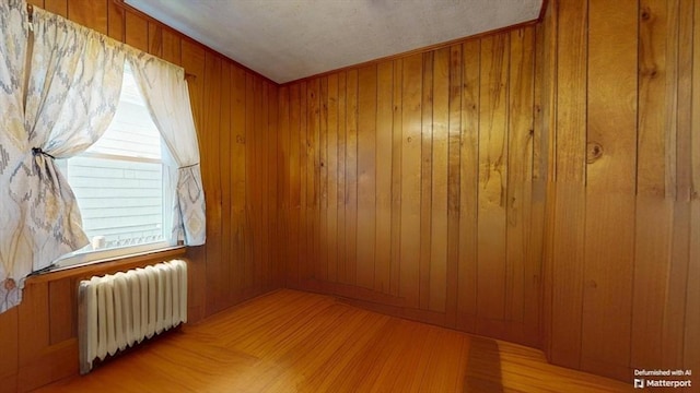 25 Garrison St, Fairhaven, MA 02719 - unfurnished room featuring radiator heating unit, healthy amount of natural light, wood walls, and wood finished floors