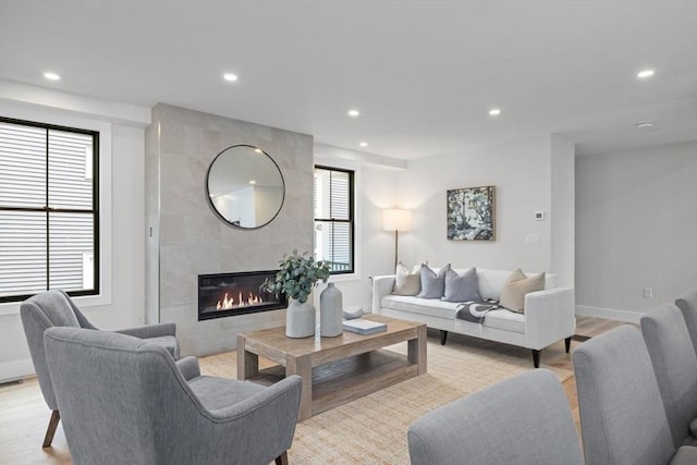 living room with a tiled fireplace and light hardwood / wood-style floors