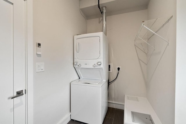 clothes washing area featuring stacked washer and clothes dryer and baseboards