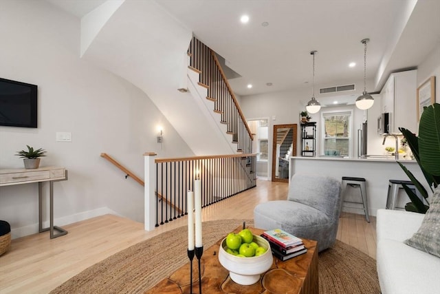 living area featuring light wood-style floors, recessed lighting, stairs, and baseboards