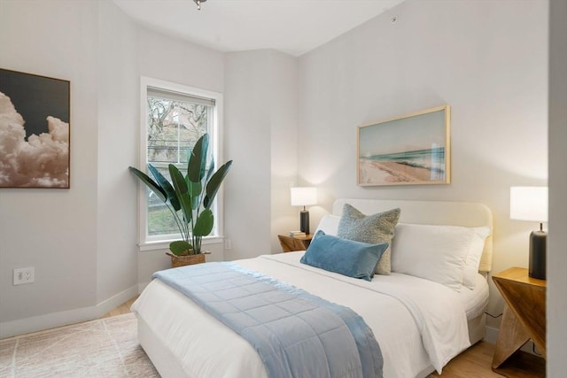 bedroom featuring multiple windows, baseboards, and wood finished floors