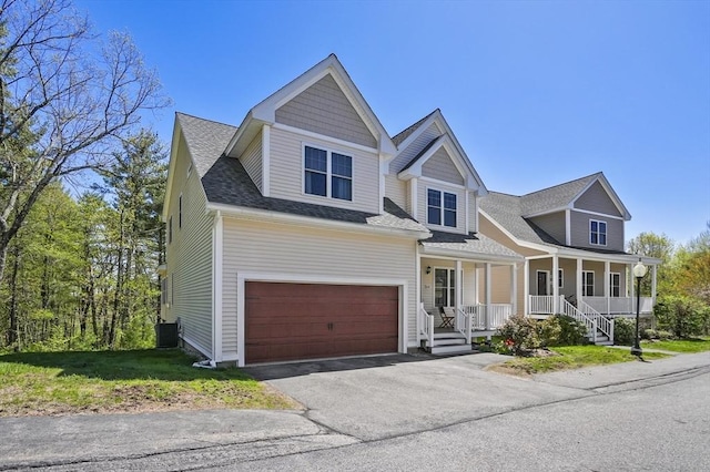 view of front of property with covered porch, an attached garage, driveway, and roof with shingles