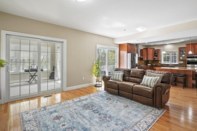 living room with baseboards, visible vents, and light wood finished floors