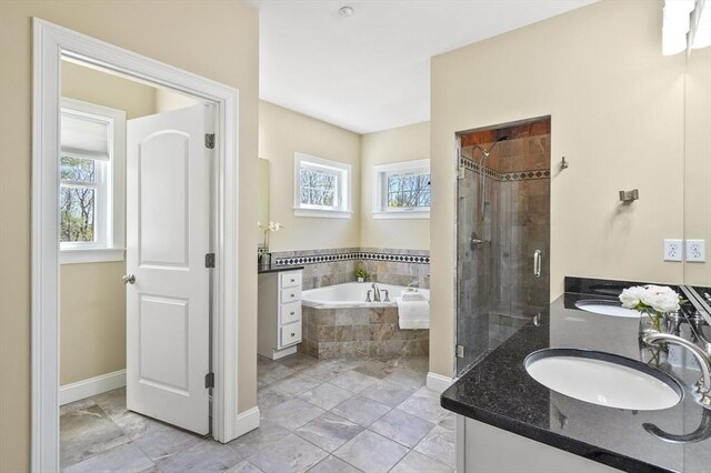 bathroom featuring a sink, double vanity, baseboards, a garden tub, and a stall shower