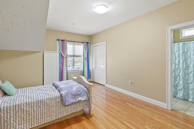 bedroom with baseboards, multiple windows, a closet, and wood finished floors