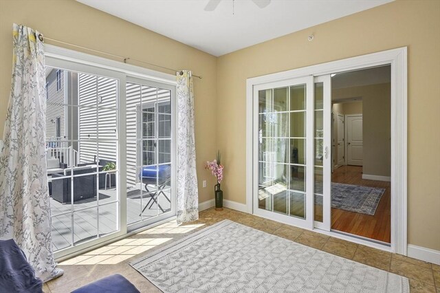 doorway with baseboards, ceiling fan, and tile patterned floors