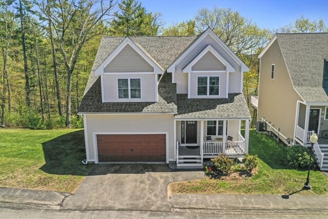 traditional home with a front lawn, covered porch, central AC unit, a shingled roof, and driveway