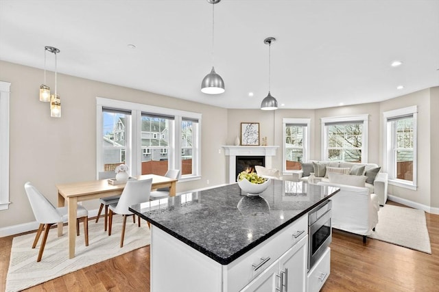 kitchen with white cabinets, pendant lighting, a kitchen island, and stainless steel microwave