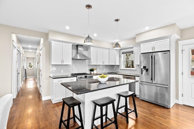 kitchen with white cabinets, sink, wall chimney exhaust hood, a kitchen island, and stainless steel appliances