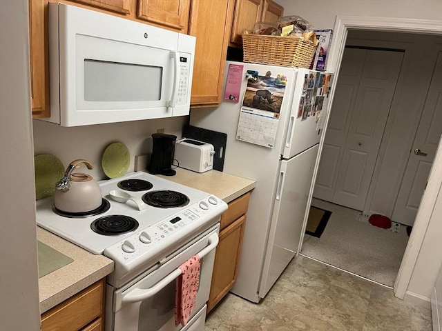 kitchen featuring white appliances, light countertops, and brown cabinetry