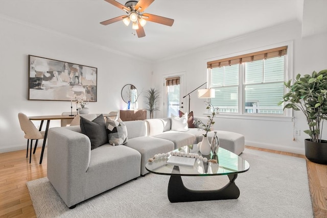 living room with light wood-type flooring, crown molding, and ceiling fan