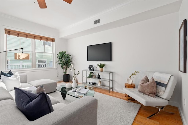 living room with hardwood / wood-style floors, crown molding, and ceiling fan