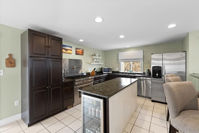 kitchen with sink, appliances with stainless steel finishes, dark brown cabinets, beverage cooler, and a kitchen island