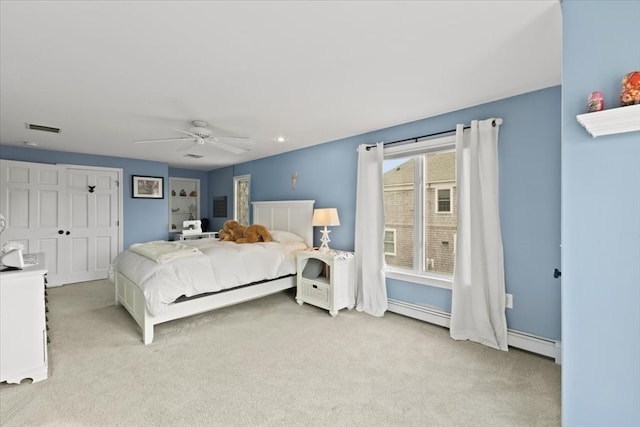 bedroom featuring baseboard heating, a closet, light carpet, and ceiling fan