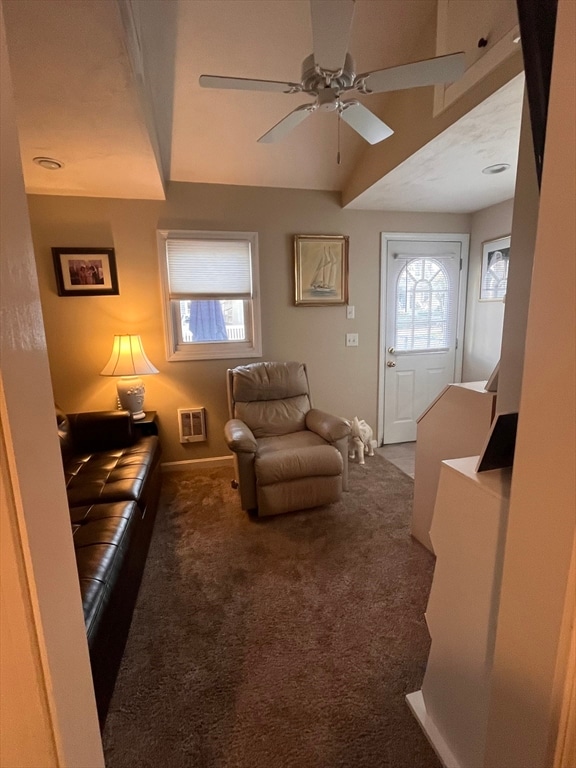 living area featuring a healthy amount of sunlight, ceiling fan, and dark carpet