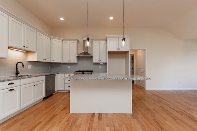 kitchen featuring light stone counters, appliances with stainless steel finishes, wall chimney range hood, and light hardwood / wood-style flooring