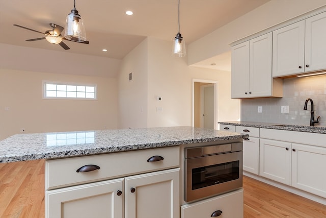 kitchen featuring light stone countertops, sink, white cabinetry, and light hardwood / wood-style floors