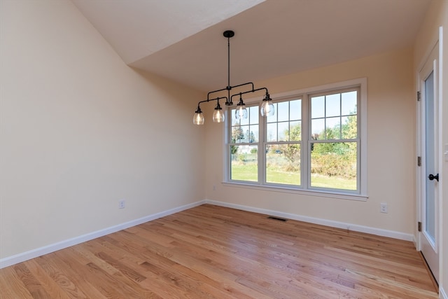 unfurnished dining area with lofted ceiling and light hardwood / wood-style flooring