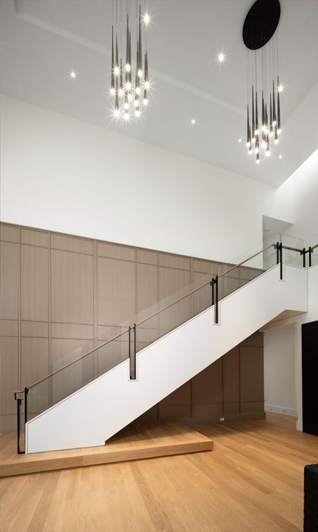 interior space with decorative light fixtures, a towering ceiling, light wood finished floors, and a barn door