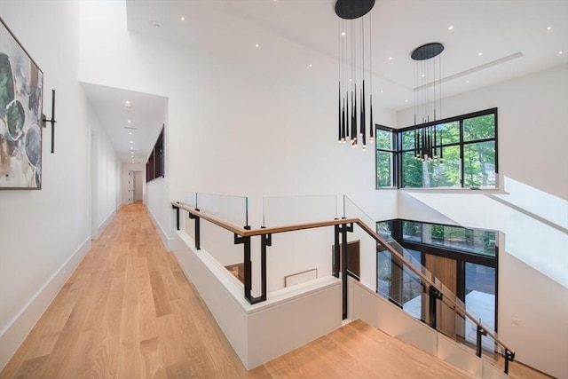 corridor with recessed lighting, a high ceiling, an upstairs landing, wood finished floors, and baseboards