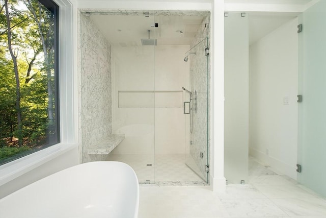 bathroom featuring marble finish floor, a freestanding tub, and a shower stall