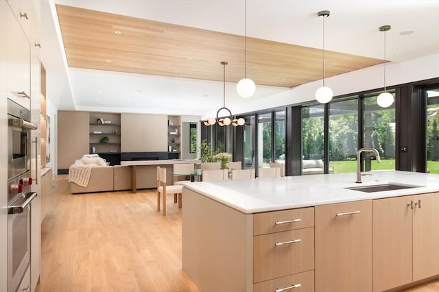 kitchen with light brown cabinets, modern cabinets, a sink, and light wood-style floors