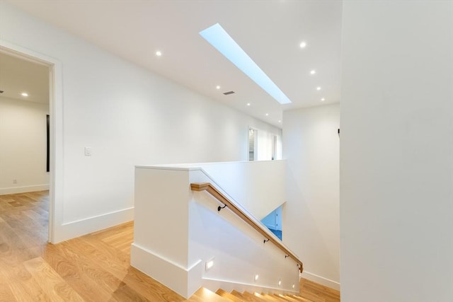 stairs featuring baseboards, a skylight, wood finished floors, and recessed lighting