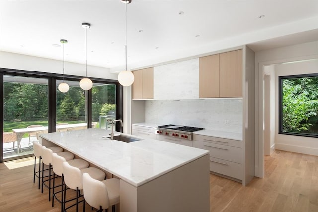 kitchen with stainless steel gas cooktop, modern cabinets, a sink, and light wood-style floors