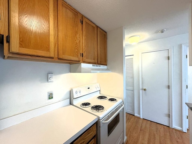101 Fletcher Unit K, Brewster, MA 02631 - kitchen with electric stove, light wood-style flooring, light countertops, under cabinet range hood, and brown cabinetry