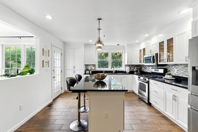 12 Paul Revere Path Unit 12, Hopkinton, MA 01748 - kitchen featuring stainless steel appliances, dark countertops, a kitchen breakfast bar, backsplash, and glass insert cabinets