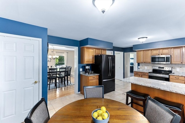 48 Logans Run, Attleboro, MA 02703 - kitchen featuring stainless steel appliances, light stone counters, a chandelier, tasteful backsplash, and light tile patterned flooring