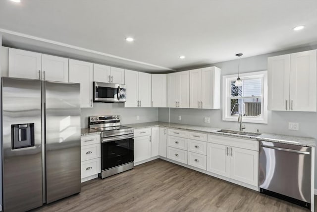 kitchen featuring dark hardwood / wood-style floors, sink, white cabinets, hanging light fixtures, and stainless steel appliances