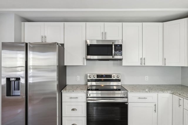 kitchen with light stone countertops, white cabinetry, and appliances with stainless steel finishes