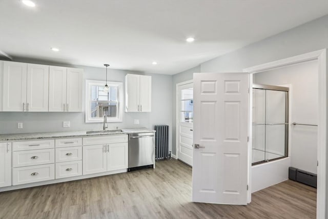 kitchen with dishwasher, sink, radiator heating unit, and white cabinets