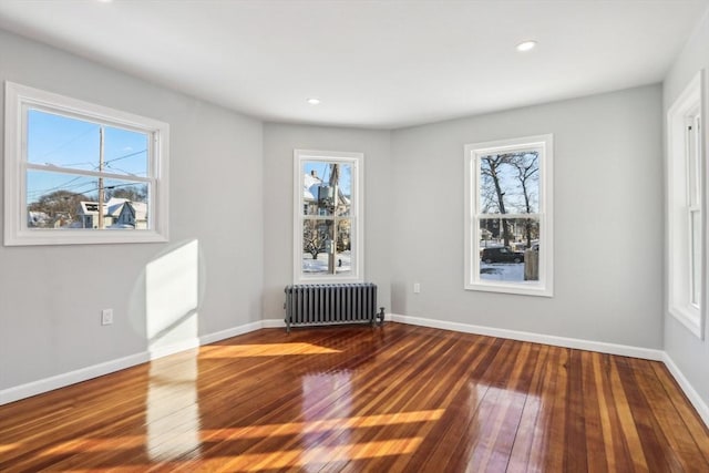 spare room with dark hardwood / wood-style floors and radiator heating unit