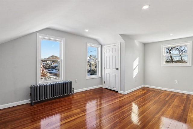 bonus room featuring dark wood-type flooring, radiator, and a wealth of natural light