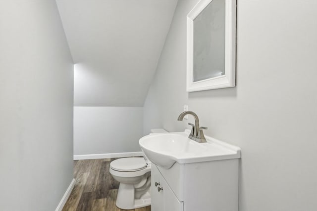 bathroom with vanity, vaulted ceiling, wood-type flooring, and toilet